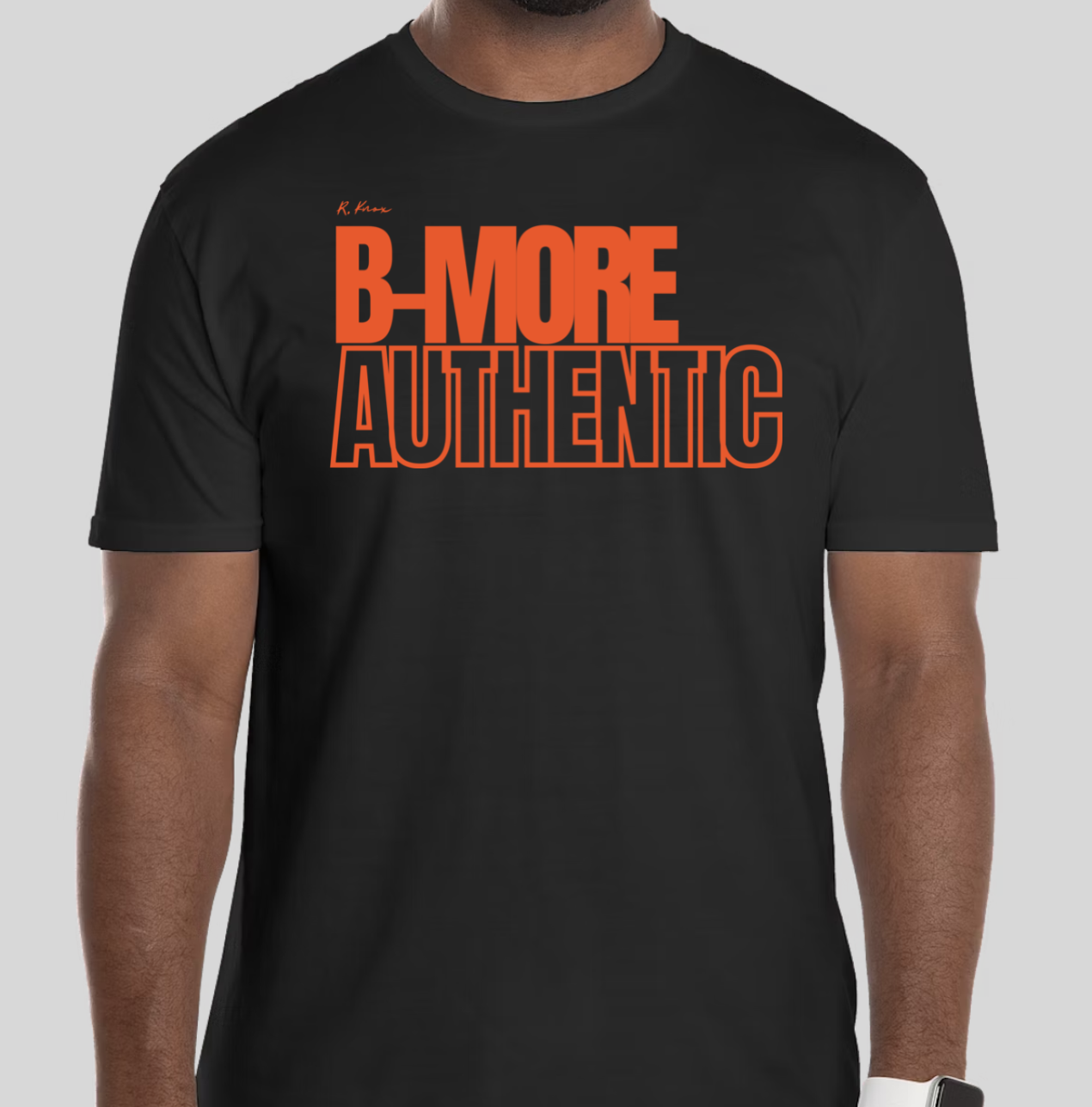 The B-More Authentic t-shirt features boxed text which spells out an abbreviated version of the word Baltimore. An altered version of the BHS logo is applied to the back of the t-shirt.